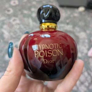 Hypnotic Poison Eau de Toilette från Dior - Säljer en elegant och förförisk Hypnotic Poison Eau de Toilette från Dior. Flaskan har en djup röd färg med en svart kork och gyllene detaljer. Perfekt för den som vill ha en doft som sticker ut och lämnar ett bestående intryck.    Den luktar vanilj med hintar av Jasmin och mandel 100ml