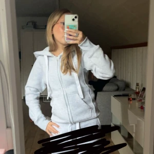 Grå hoodie med dragkedja - Säljer en bekväm och stilren grå hoodie med dragkedja och huva. Tröjan har långa ärmar och praktiska fickor framtill. Perfekt för en avslappnad look.