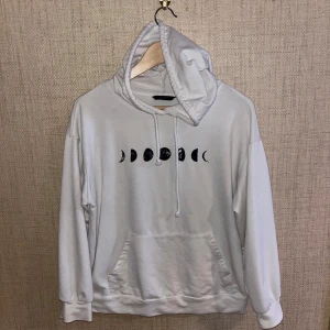 Vit hoodie med månfastryck - Säljer en vit hoodie med ett coolt månfastryck på bröstet. Hoodien har en stor ficka framtill och en justerbar huva.