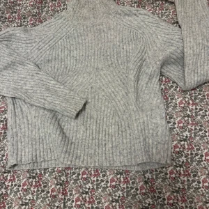 Stickad halvpolo  - Grå stickad tröja i halvpolo. Storlek M, liten i storleken — passar S/XS. Defekt på kragen och inuti. Se bild. 50 kr