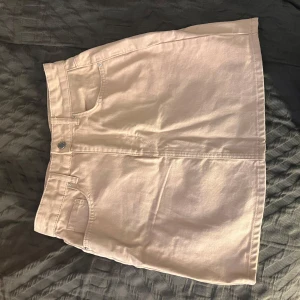 Beige jeanskjol - Snygg beige jeanskjol med klassisk femficksdesign och knappstängning fram. Perfekt för en avslappnad stil. Kjolen har en kort längd och är tillverkad i ett robust denimtyg.