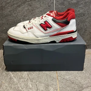 New Balance 550  - Snygga New Balance 550 sneakers i vitt med röda och svarta detaljer. Det är bra kvalitet på skorna och är väldigt sköna och perfekta under dom här tiderna, skorna har några små skador men är inte synliga tex lite häll skrapning på sulan. St 45,5 med orginal lådan. Skriv vid mer frågor.