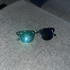 Solglasögon från Ray-Ban - Snygga solglasögon från Ray-Ban med en klassisk design. Bågarna är i en mörk färg med sköldpaddsmönster och glasen är mörka. Perfekta för en stilren look.