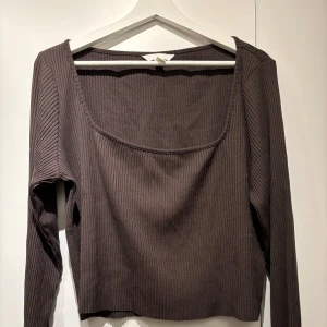 Brun ribbad tröja - Säljer en stilren brun ribbad tröja med fyrkantig halsringning. Tröjan har långa ärmar och en bekväm passform, perfekt för kyligare dagar. Ett mångsidigt plagg som passar till många olika outfits.