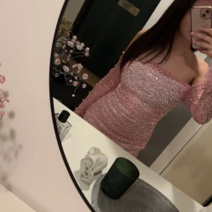 Rosa paljettklänning - Säljer en glittrig rosa klänning med paljetter och offshoulder-design. Klänningen har långa ärmar och en tight passform som framhäver figuren. Perfekt för en festlig kväll!