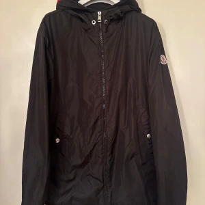 Moncler  - Moncler windbreaker. Storlek 4, färg svart. Fint skick utöver pinehole som visas. Pris 2750kr.