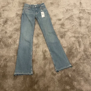 Blå bootcut jeans från Mango - Snygga blå bootcut jeans från Mango i klassisk denimstil. De har en låg midja och en stilren design med fem fickor och dragkedja. Jag har endast testat de och sprättat upp de nertill. Säljer då de är lite för korta för mig som är 175 cm.