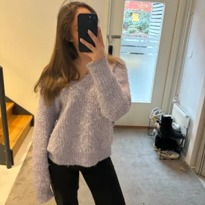 Ljuslila fluffig tröja från Bisou's Project - Säljer en supermjuk och fluffig ljuslila tröja från Bisou's Project. Tröjan har en v-ringad design och långa ärmar, perfekt för kyligare dagar. Materialet är en blandning av polyester och elastan vilket ger en skön passform. Perfekt för att mysa i hemma eller ute.💜