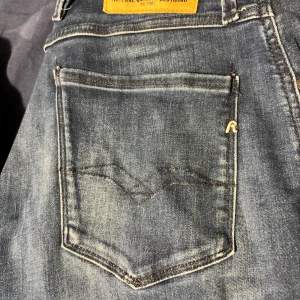 Blå jeans från Replay - Snygga blå jeans från Replay med klassisk femficksdesign och diskret logga på bakfickan. Jeansen har en dragkedja och är perfekta för en avslappnad stil. De har en lätt tvättad look som ger en cool touch.