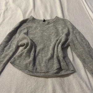 Grå stickad tröja från Divided - Mysig grå stickad tröja från Divided. Den har en rund halsringning och långa ärmar med ribbade muddar. Perfekt för kyligare dagar.