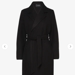 Svart kappa från Vero Moda - Elegant svart kappa från Vero Moda med knytbälte i midjan. Den har en klassisk krage och långa ärmar, perfekt för kyligare dagar. Stilren och tidlös design som passar till många olika outfits.