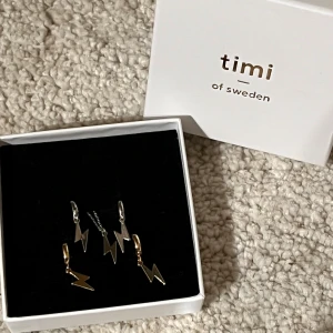 Blixtformade örhängen från Timi of Sweden - Snygga örhängen och ett halsband i blixtform från Timi of Sweden. Setet innehåller både guld- och silverfärgade örhängen. Har inte kommit till användning och Kommer i förpackningen.