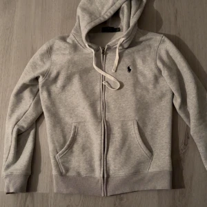 Grå Ralph Lauren Hoodie - Säljer en äldre modell av Ralph Lauren. Använd en gäng sen bara legat i garderoben sà den är i nyskick. M men mindre i storleken