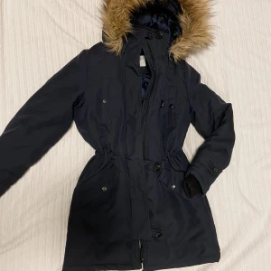 Svart parkajacka från Vero Moda - Snygg svart parkajacka från Vero Moda med fuskpäls på huvan. Jackan har dragkedja och knappar framtill samt praktiska fickor. I bra skick ☺️