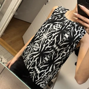 Svartvit mönstrad ärmlös topp - Snygg ärmlös topp med ett coolt svartvitt mönster. Perfekt för att ge en cool touch till din outfit. Toppen har en rund halsringning och ett luftigt fall.