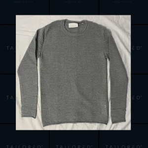 Grå långärmad tröja från Tailored Originals - En grå långärmad tröja från Tailored Originals i 100% bomull. Tröjan är formad med ränder på i materialet, och är mjuk och bekväm. Tröjan är använd ett fåtal gånger vilket synns på dess fina skick utan några skador eller skavanker  Tröjan är i storlek S, normal i storleken. Mått följer nedan.   Axelbredd: 40cm Längd: 65cm Ärmlängd: 63cm Behöver du fler mått? Tveka inte att höra av dig!  Skickas inom 24h efter beställning. SENAST 48h efter beställning. Vid fler frågor, hör av dig!🙂