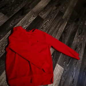 Röd tröja från Polo Ralph Lauren - Säljer en snygg röd tröja från Polo Ralph Lauren. Tröjan har en klassisk design med långärmade ärmar och en liten broderad logotyp på bröstet. Perfekt för en stilren look. Har använt den ungefär 2 gånger. Kan även gå ner i pris