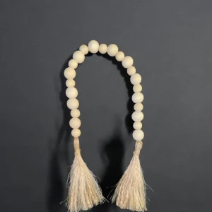 Dekorativt pärlhalsband med tofsar - Snygg och stilren pärlgirlang med stora, runda pärlor i en naturlig beige ton.Girlangen avslutas med två dekorativa tofsar som ger en bohemisk känsla. 