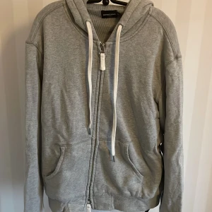 Grå hoodie från Earnest Sewn - Säljer en grå hoodie från Earnest Sewn i storlek M. Den är supermjuk och perfekt för kyliga dagar. Har en dragkedja framtill och praktiska fickor. Huvan har vita snören för justering. Perfekt för en avslappnad stil!