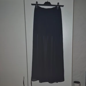 Genomskinlig Maxi Skirt - Genomskinlig Maxi Skirt med kort kjol under som sitter ihop. Slits hela vägen upp på vänster sida. 100% polyester   Nyskick. Använd 1-2 gånger. 