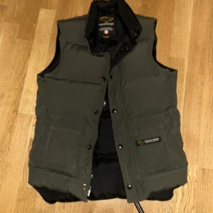 Canada goose väst - Äkta Canada goose väst. En vintage modell. Sitter skönt och snyggt, varm. Passar typ Xs/S beroende på hur man föredrar att den ska sitta. Jättebra skick känns typ som ny, har själv aldrig använt den. 