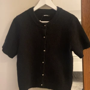 Stickad T-shirt  - Super fin stickad tshirt med knappar. Kommer ej till användning. Super fin både knappt men också uppknäppt. Ny!! Ordinarie pris är 399