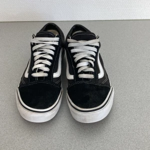 Svarta sneakers från Vans - Säljer ett par klassiska svarta Vans sneakers i storlek herr 40. De har en snygg vit sula och vita snören som ger en stilren look. Skorna är i bra skick med minimal slitage på sulan. Perfekta för vardagsbruk eller en avslappnad stil. Passar både vår och höst!