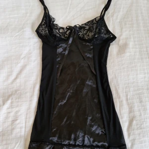 Nattlinne med spets - Vackert, skirt nattlinne med öppen rygg! 🖤 Spets och rosett vid bysten, snörning i ryggen. Inbyggda strumpeband.  Köpt här på Vinted, aldrig använt av mig. Inga defekter.  Hör gärna av er vid frågor! 