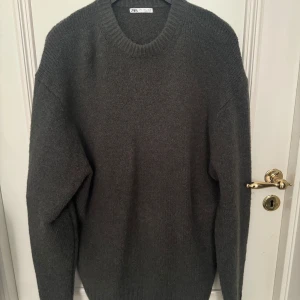 Grön stickad tröja från Zara - Säljer en stilren grön stickad tröja från Zara. Perfekt för kyliga dagar med sin mjuka och varma känsla. Tröjan har en klassisk rund hals och långa ärmar, vilket gör den idealisk nu på hösten. Passar perfekt till jeans eller chinos!