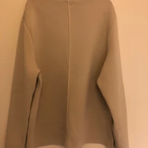 Beige tröja från Wera - Säljer en stilren beige tröja från Wera i storlek L. Den är gjord av en mjuk blandning av viskos, polyamid och elastan, vilket gör den både bekväm och stretchig. Perfekt för höst och vår med sin enkla design och långa ärmar. Passar till både vardag och lite finare tillfällen.