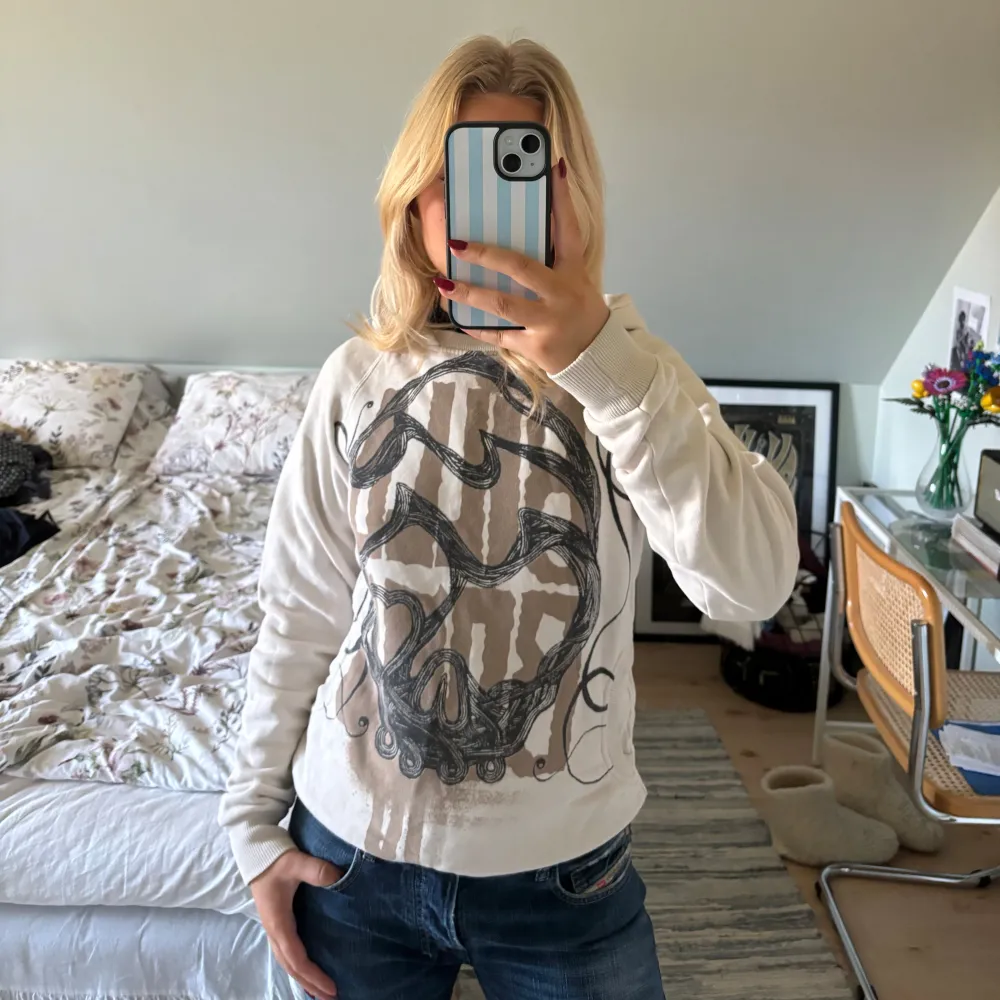 Säljer en snygg vit hoodie med ett coolt grafiskt tryck i svart och brunt på framsidan🤍. Hoodies.