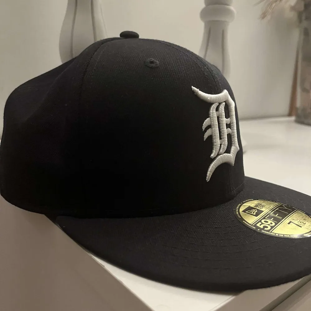 Säljer en snygg keps från New Era med ett broderat vitt emblem på framsidan. Kepsen är i storlek 7 1/2 (59.6 cm) och har en klassisk 59FIFTY passform. Perfekt för både vardag och sportiga tillfällen!. Accessoarer.