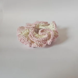 Handgjord virkad scrunchie i rosa och vit - Superfin handgjord scrunchie som är virkad i mjuka pastellfärger. Den har en härlig kombination av rosa och vit som ger en söt och romantisk look. Perfekt för att piffa upp vilken frisyr som helst, oavsett om det är en vanlig dag eller en speciell tillställning. Den är elastisk och passar de flesta hårtyper.