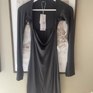 Grå långärmad klänning från Bershka - Säljer en stilren grå långärmad klänning från GinaTricot. Klänningen har en elegant fyrkantig urringning och är i ett mjukt, stretchigt material som ger en tight passform. Perfekt för en utekväll eller fest!❤️ Aldrig använd med lapparna kvar 🥰