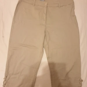 Byxor - Beige byxor med snörning på sidorna. Byxorna har en rak passform och är i bra skick. Är lite kort säljs för 60.