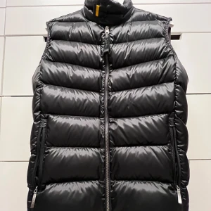 Svart dunväst från Parajumpers - Säljer en nice o varm dunväst från Parajumpers. Västen har knappast använts och är perfekt för kyliga höst- och vinterdagar. Den har en hög krage och är i storlek Y-M (Youth - Medium). Passar bra för kalla kvällar/dagar. Ordinarie pris 4500kr.