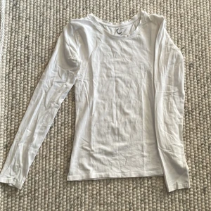 Vit långärmad tröja - Säljer en enkel och stilren vit långärmad tröja. Perfekt för lager-på-lager under höst och vår. Tröjan är i ett mjukt och bekvämt material, vilket gör den idealisk för vardagsbruk.