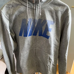 Nike hoodie - Nike grå hoodie med luva och dragkedja i mitten. Storlek medium.
