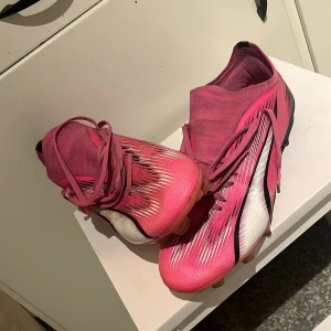 Puma fotbollsskor  - Jag säljer ett par PUMA ULTRA ULTIMATE FG/AG PHENOMENAL - POISON PINK/VIT/SVART HERR. Stl 42 27cm. Andvänt de i 1 månad och sen vart de för små Original pris 1800kr 