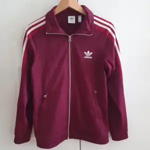 Track Jacket med knappar på ärmarna i klassisk adidas -stil. Mindre noppror vid fickorna, annars gott skick. 