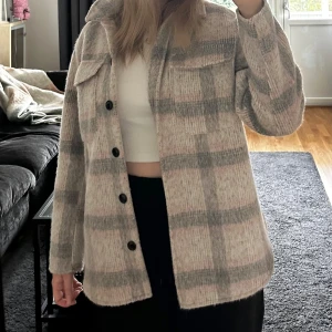 ONLY kappa - Säljer en superfin rutig jacka från ONLY i storlek M. Färgen på jackan är ljusrosa och grå. Perfekt för höst och vår när du vill vara både varm och stilren. 🧥✨