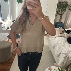 Finstickad t-shirt - Finstickad t-shirt från Kappahl. Helt oanvänd med lappar kvar! Jättefin till både höst och vår. Brun/beige i färgen. Den är lite v-ringad och har en liten krage. Det är även en liten slit i sidan som man ser på bild 4.