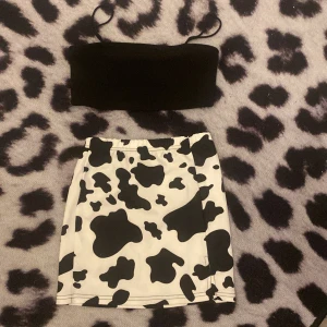 Ett sätt med ko mönstrad kjol - Svart Crop top med en ko mönstrad kjol, kjolen har även en slipts, köptes för 40 kr använd några få tal gånger, rent skick & inte trasig. Pris går att diskutera. 