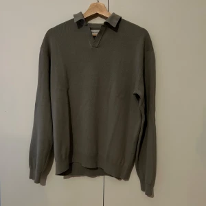 Grå tröja med krage - Säljer en stilren grå tröja från These Glory Days. Den har en klassisk krage och är långärmad, perfekt för både vardag och lite finare tillfällen. Materialet känns mjukt och bekvämt, och den har en normal passform.