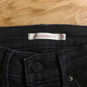 Bootcut jeans Levis  - Bootcut jeans från Levis. Använda men i gott skick. Figurnära med en utsvängd bootcut. Färg lite grå/svart. 