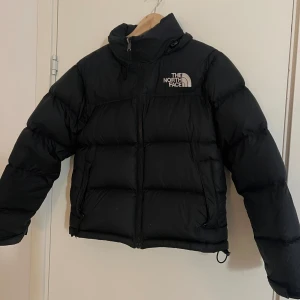 The North Face Jacka - Jackan är i väldigt bra skick förutom en defekt som syns pa sista bilden. Det är en liten lagning pả ena armen, syns knappt men priset kan diskuteras pga det😊 Modell: Women's 1996 Retro Nuptse Jacket Storlek S Nypris 3899kr