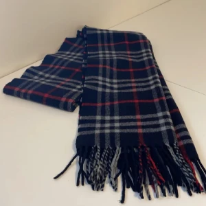 Burberry halsduk - Säljer en stilren rutig halsduk från märket burberry. Den är gjord av mjuk ull och har fransar i ändarna som ger en extra touch. Perfekt för att hålla sig varm under höst och vinter. Passar både till vardags och lite finare tillfällen!