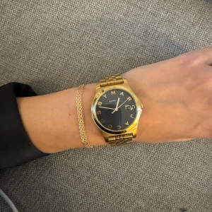 Marc by Marc Jacobs klocka - Marc By Marc Jacobs klocka - Marc by Marc Jacobs The Slim Gold/Black MBM3315  En batteridriven kvartsklocka i mycket fint skick och som är vattentålig.