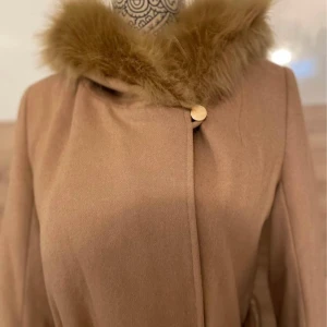 Kappa beige  - Snygg kappa från märket chiara forthi - ej äkta päls, knappt använd! I jätte fint skick - nypris 1500 kr Strl 34  Finns i Norrköping 