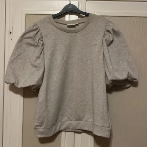 Mysig kortärmad topp - Jättefin och mysig topp med puffiga ärmar! Aldrig använd och har små guldiga korn invävt i tyget vilket gör att den passar perfekt för jul eller nyår! Nypris: 299kr